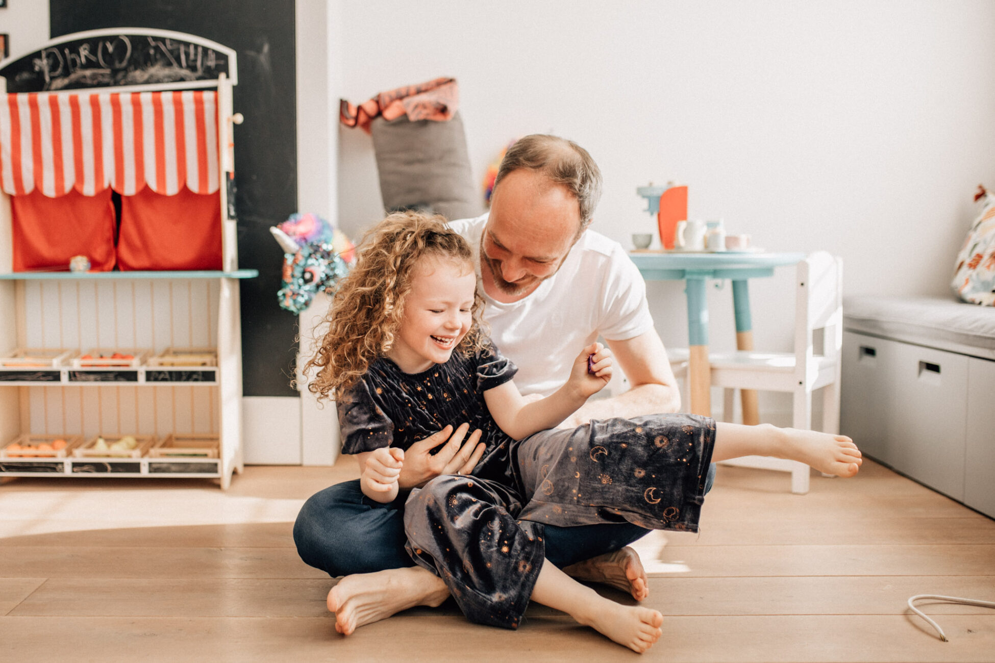 Father and daughter playing in the floor, during a Family photography session at home, in Amsterdam, The Netherlands